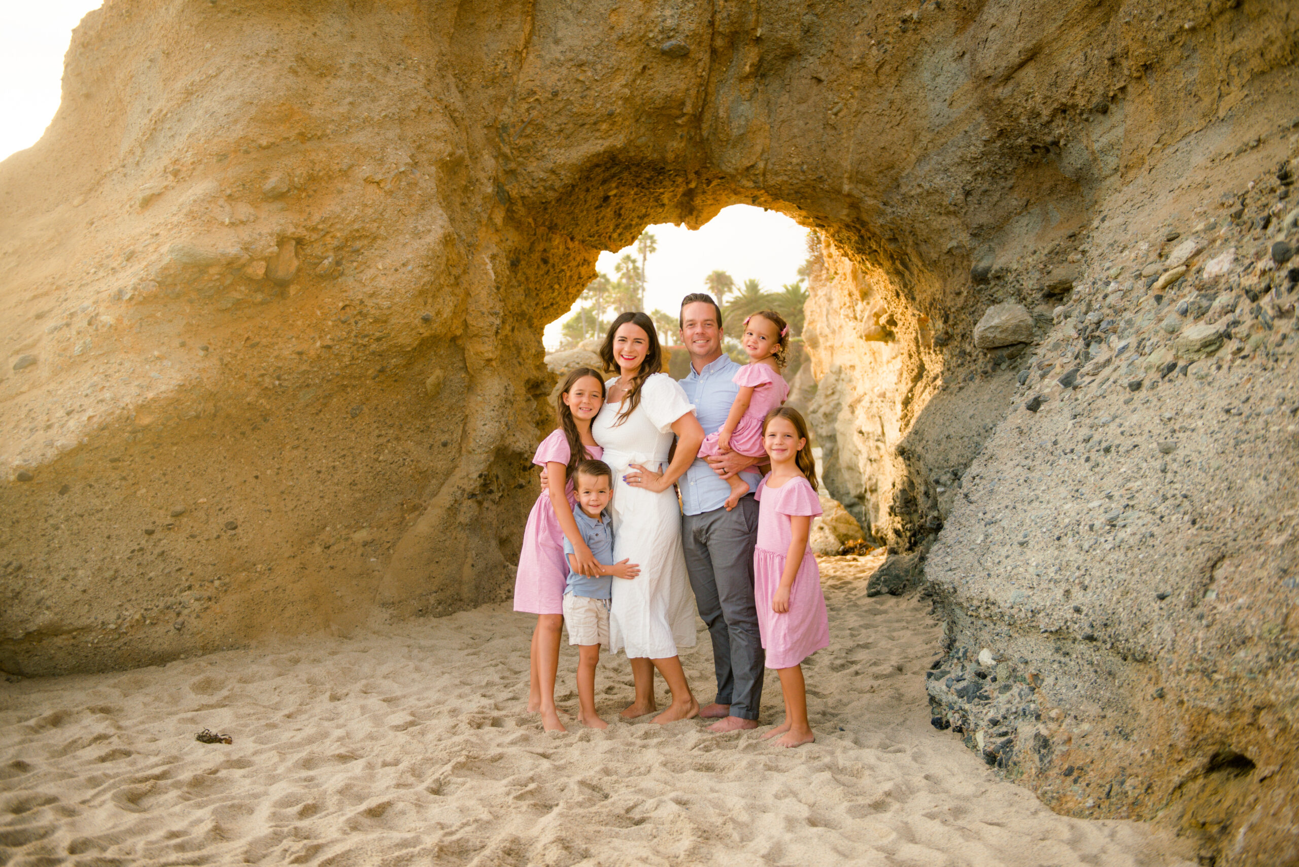 happy family smiling together under an arch at the beach