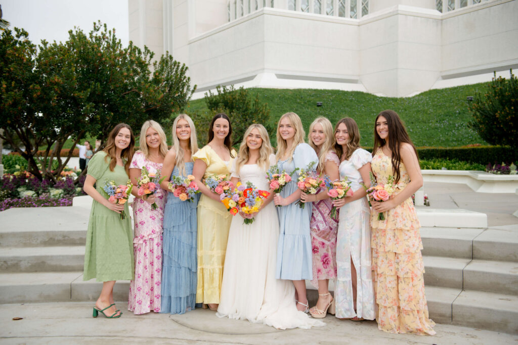 beautiful bride with her bridesmaids in colorful dresses posing in front of the san diego lds temple