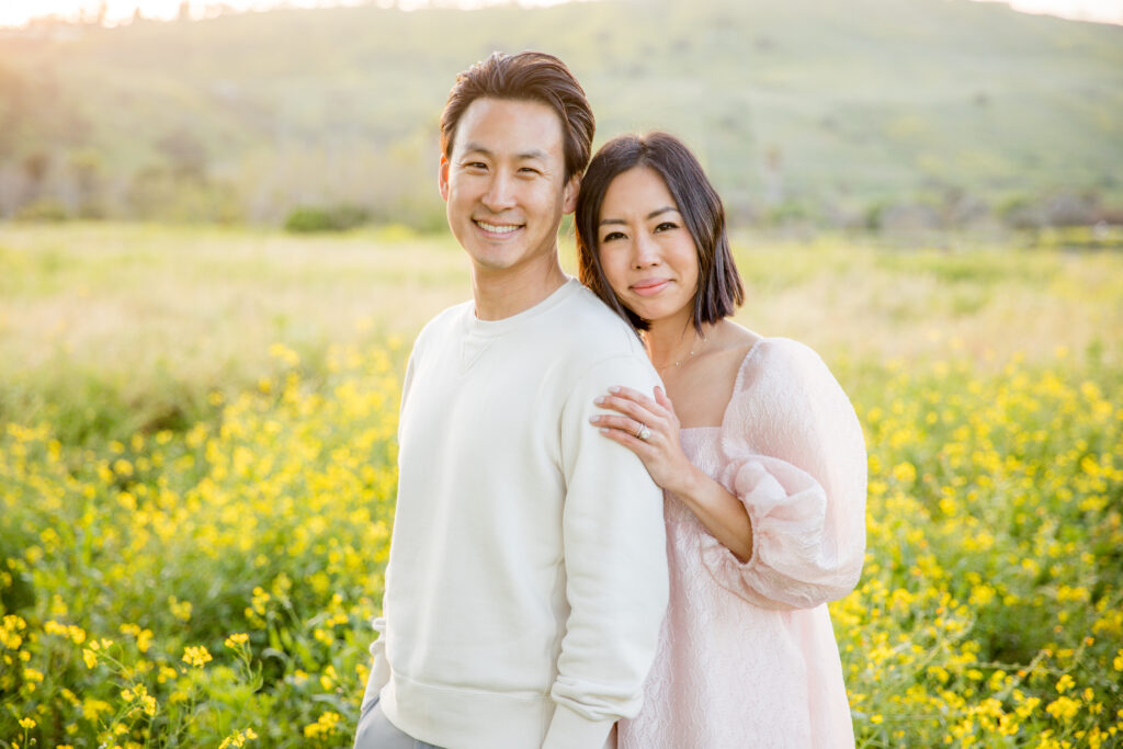beautiful couple hugging and posing for a picture in a yellow wildflower field