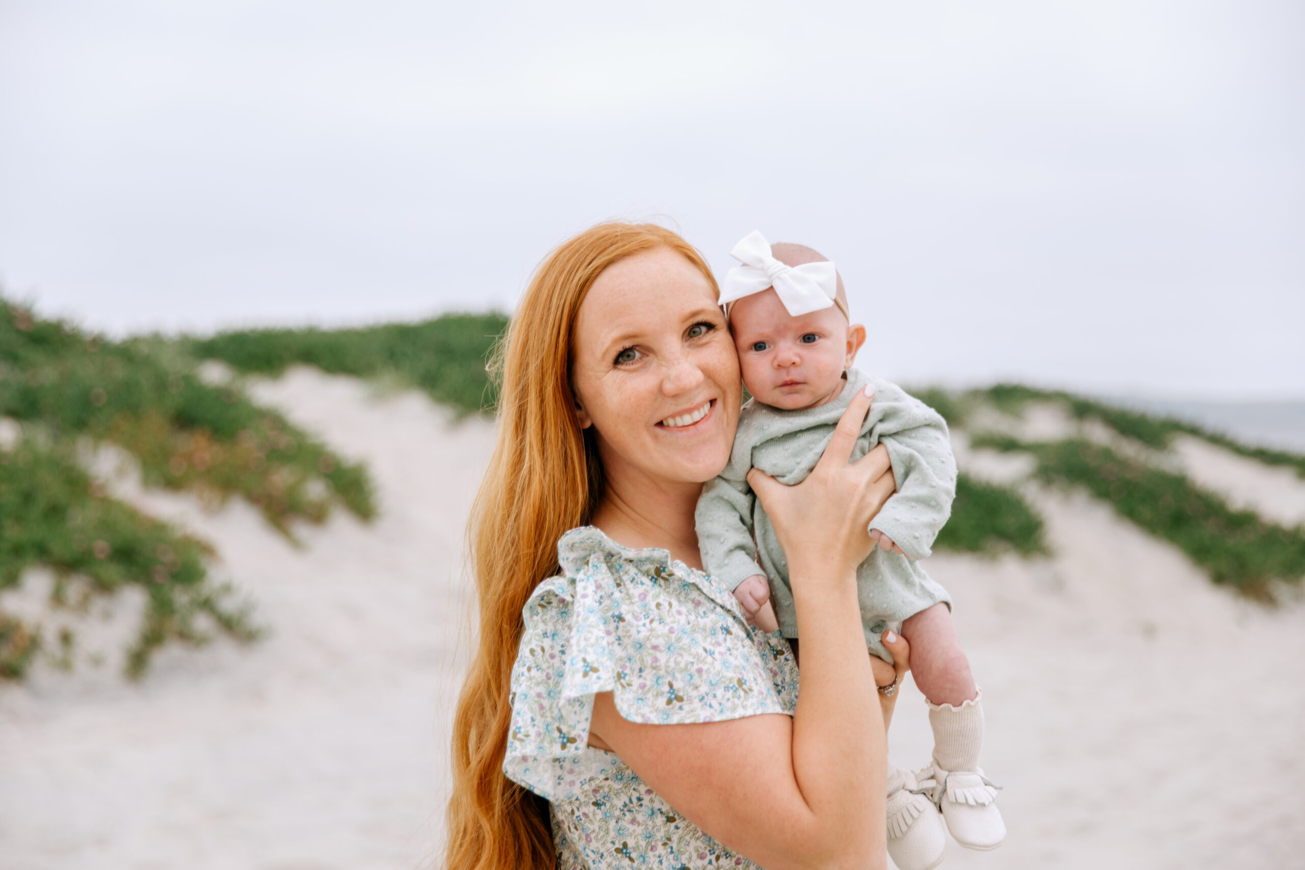 beautiful red headed mom holding her newborn baby daughter during family photos in san diego