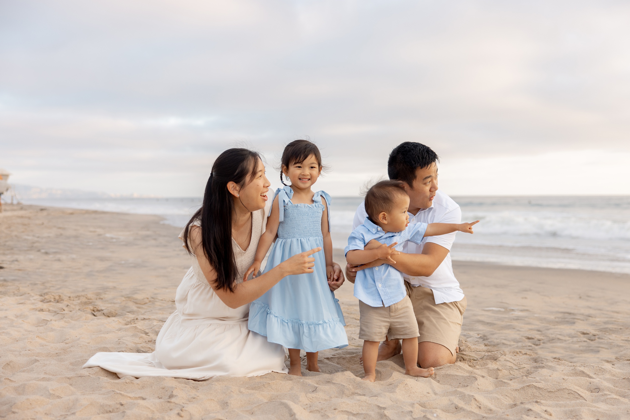 A happy family of 4 explore a beach at sunset