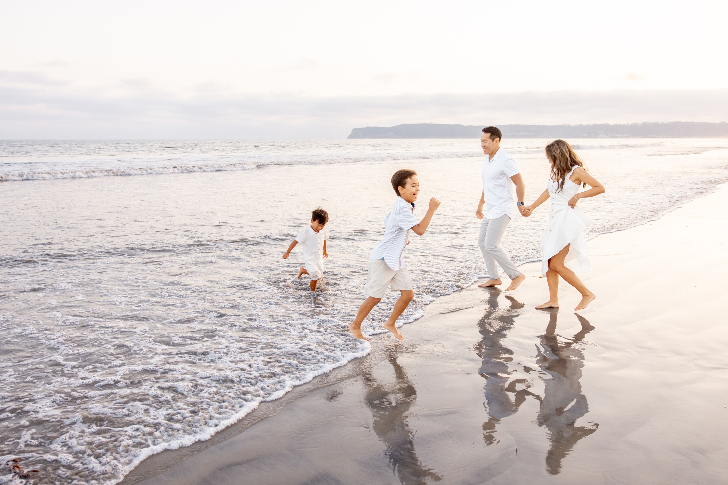 A happy family runs in the water while laughing in white clothes